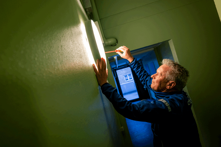 Ejendomsfunktionær John Sebber Larsen skifter en pære i en lampe. || Indkob Kbh Sebber Web