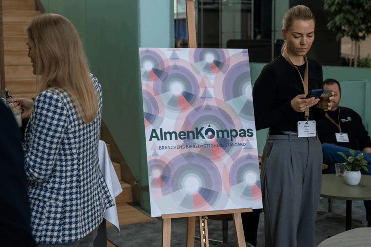 Staffeli med en AlmenKompas-plakat. || GF Almenkompas Web